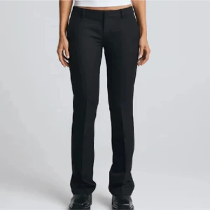 Vera kostymbyxor lowwaist från Bikbok  - Snygga svarta kostymbyxor med bootcut-stil. De har en klassisk design och en bra passform. Perfekta för en stilren look. Slits längst ner. Mått: 38cm midja, 81cm innerbenslängd. Säljer pga förstora! 