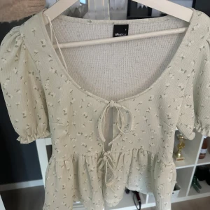 Ljus grön topp!! - Säljer denna ljus gröna toppen från Gina Tricot, den har två knyten vilket gör att storleken är reglerbar! Den har små fina blom-detaljer. Är helt ny och oanvänd, storlek S💚