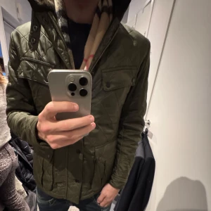 Grön quiltad jacka från Barbour - Säljer en snygg grön quiltad jacka från Barbour. Jackan har en stilren design med dragkedja och knappar framtill. Perfekt för höst och vår med sin långärmade passform och praktiska fickor. En klassisk jacka för den stilmedvetna. Medium i storlek hör av er om ni har frågor gällande jackan kan gå ner i pris vid en snabb affär skick 9/10