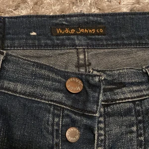 Nudie Jeans - Snygga blå jeans från Nudie Jeans med lowwaist och fyra knappar där fram. De har även en speciell, väldigt snygg, design med ljusare ”fläckar” och snygg design på bakfickorna. Ser helt och hållet oanvända ut. Pris kan förhandlas!