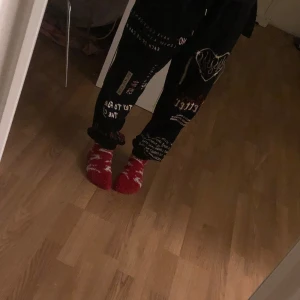 Röda byxor med vitt mönster - Säljer ett par mysiga röda byxor med ett vitt mönster. Perfekta för att hålla bena varma under kalla dagar. Byxor har en bekväm passform och är idealiska för att mysa hemma.