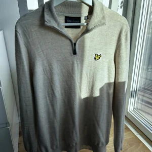 Beige tröja med dragkedja från Lyle & Scott - Säljer en stilren beige tröja från Lyle & Scott med dragkedja vid halsen och deras ikoniska logga på bröstet. Perfekt för en avslappnad men snygg look. Passar bra till både jeans och chinos.                  Hör av er vid intresse/frågor!