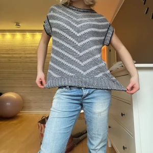 Svartvit mönstrad topp - Säljer en snygg svartvit väst med ett zigzag-mönster. Västen har korta ärmar och en rund halsringning. Perfekt för en avslappnad stil.