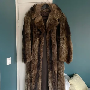 Brun äkta pälsjacka - Säljer en lång och lyxig brun äkta pälsjacka med en klassisk design. Jackan har långa ärmar och en elegant krage. Finns en litet hål i ryggen men annars finns det inga öppna hål