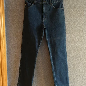 Mörkblå jeans från Flash - Snygga mörkblå jeans från Flash med klassisk femficksdesign och knappgylf. Perfekta för en avslappnad stil. De har en rak passform och är tillverkade i slitstarkt denim.