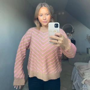 Beige och rosa stickad tröja - Säljer en mysig stickad tröja i beige med rosa ränder. Tröjan har en avslappnad passform och långa ärmar, perfekt för kyliga dagar. Den har ett klassiskt mönster som ger en trendig touch. Perfekt för höst och vinter! Från Mango och jätteskönt material.
