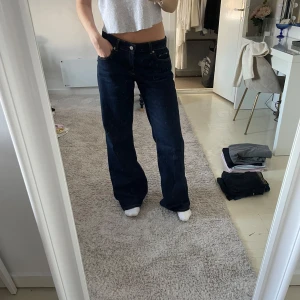 Mörkblå jeans från NA-KD - Sååååå snygg mörkblå jeans från NA-KD i modellen ”jeans med låg midja” . De har en rak passform och är lågmidjade. Helt nya! Köpta i november 2024 men säljer nu då jag behöver en mindre storlek! Helt nytt skick förutom lite slitage i slutet på byxorna(se sista bilden). Orginalpris 699kr.