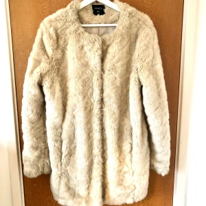 Crèmefärgad fuskpäls från Lindex - Säljer en supermjuk och fluffig fuskpälsjacka från Lindex. Köpt begagnad men sparsamt använd så i fint skick! Storlek S men passar även mig som oftast är M. Säljes pga inte min stil längre.  (Finns på fler säljsidor)