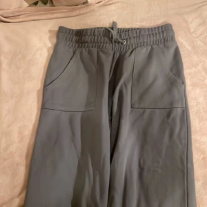 Grå mjukisbyxor med snörning - Säljer ett par bekväma grå mjukisbyxor med elastisk midja och snörning. Byxorna har praktiska fickor framtill och är perfekta för en avslappnad stil.