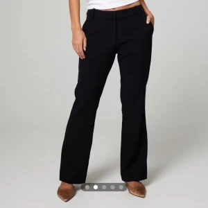 Svarta kostymbyxor - Snygga svarta kostymbyxor med en klassisk bootcut-stil. De är en mid waist och är perfekta för en stilren look. Byxorna är tillverkade i ett bekvämt material som ger en elegant passform. Original pris 499! Finns täcken på användning men är fortfarande som nya! De är små i strl! 46 motsvarar L/XL