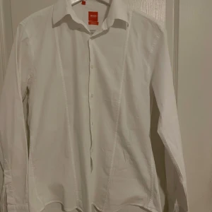 Vit skjorta från BOSS - Snygg vit skjorta från BOSS i slim fit. Skjortan har långa ärmar och knappar framtill. Perfekt för en stilren look.