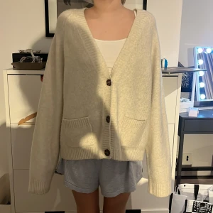 Beige kofta från Uniqlo - Mysig beige/vit kofta från Uniqlo med knappar framtill och två fickor där fram. ❤️ nypris 450kr