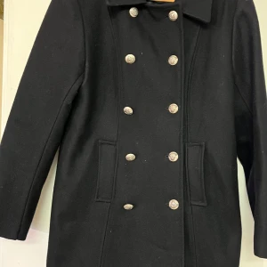 Svart skepparkavaj från Pigalle - Snygg svart skepparkavaj från Pigalle med dubbelknäppning och stilrena knappar. Perfekt för en klassisk look. Kavajen har en tidlös design och är ett måste i garderoben.
