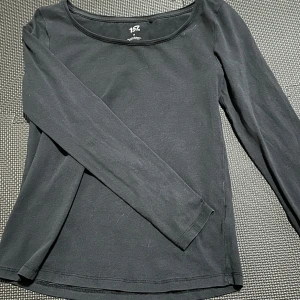 Svart långärmad topp från 157 - Säljer en stilren svart långärmad topp från 157. Tillverkad i en mjuk bomullsblandning med elastan för extra komfort. Perfekt för en enkel och snygg look.