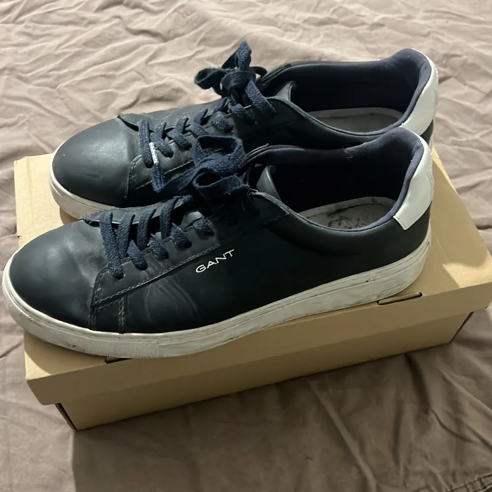 Snygga mörkblå sneakers från Gant med röd/blå sula och snörning. Skorna har en stilren design med Gant-logga på sidan. Perfekta för en avslappnad stil.. Kengät.