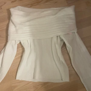 Vit ribbad offshoulder tröja från Nelly - Säljer en stilren vit ribbad offshoulder tröja från Nelly. Tröjan har långa ärmar och en slouchy passform som ger en avslappnad look. Perfekt för att kombinera med jeans eller kjol för en trendig outfit.