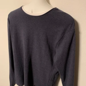 Mörkblå tröja med rund hals - Säljer en stilren mörkblå tröja med rund hals och långa ärmar. Perfekt för en avslappnad look. Tröjan har en liten etikettdetalj vid nederkanten. Storlek S