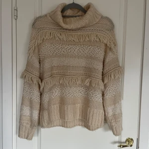 Beige stickad tröja  - Mysig beige stickad tröja från hm med fransdetaljer och polokrage. 
