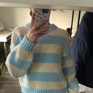 Randig stickad tröja från Vero Moda - Mysig stickad tröja från Vero Moda i ljusblått och beige. Tröjan har ett randigt mönster och långa ärmar. Perfekt för kyliga dagar med sin mjuka och bekväma passform. Har dock använts flitigt så den är lite nopprig men annars är den perfekt!