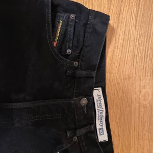 Svarta jeans från Diesel - Snygga svarta jeans från Diesel med klassisk design. De har en rak passform och är perfekta för en stilren look. Jeansen har en knappgylf och femficksmodell.