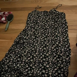 Blommig långklänning med smala axelband - Säljer en söt långklänning med blommigt mönster i svart och vitt. Klänningen har smala axelband och en luftig passform, perfekt för varma dagar. 🌸
