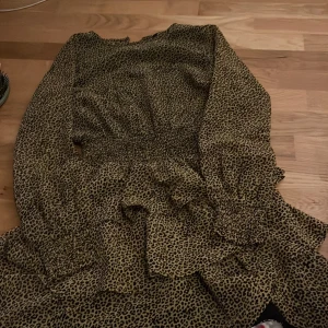 Leopardmönstrad klänning - Snygg leopardmönstrad klänning med volangdetaljer och långa ärmar. Perfekt för att sticka ut med ett djärvt mönster. Klänningen har en smickrande passform och är gjord i ett mjukt material.