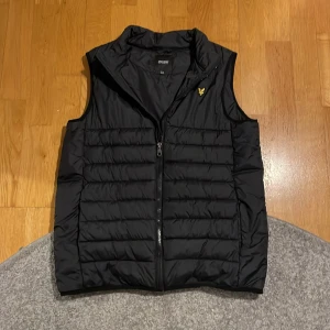 Svart dunväst från Lyle & Scott - Skön vår väst säljes pga den är för liten. Bra pris eftersom jag vill bli av med gamla jackor/västar. Skriv för frågor och bilder. Priset är ej hugget i sten. 