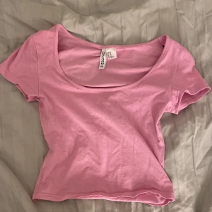 Rosa kortärmad topp från H&M Divided - Säljer en söt rosa kortärmad topp från H&M. Toppen är urringad och lite kort men jätte snygg på. Är i storlek xs