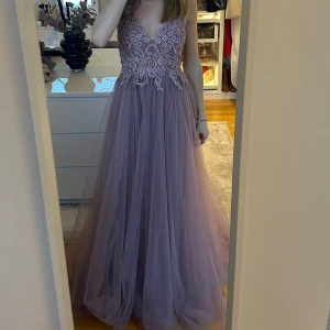 Gammeldagsrosa/lila tyllklänning med spetsdetaljer - Helt ny balklänning från Venitti, köpt på Weeding Store Malmö. Endast provad. Klänningen har snöring i ryggen som går att justera (kan bli större storlek samt mindre), klänningen är i strl 36 och är för lång för mig som är 161cm, då jag ej sytt upp den. Klänningen har även en slits under tyllet. Jättefin och perfekt till balen!🩷Skriv för fler bilder! Nypris: 3500kr