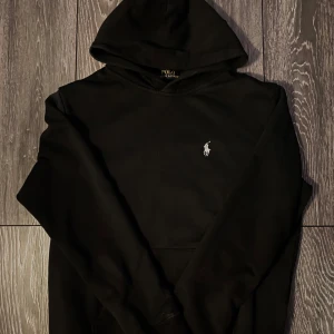 Svart hoodie från Polo Ralph Lauren - Säljer en stilren svart hoodie från Polo Ralph Lauren då den inte kommer till andvändning, Storleken är L i junior  (motsvarar S/XS) Väldigt bra skick, inga fel.