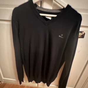 Svart tröja från GANT - Säljer en stilren svart tröja från GANT med v-ringning. Tröjan har långa ärmar och en diskret logga på bröstet. Perfekt för en klassisk look. Säljer den inte min stil, den e som ny, pris kan diskuteras 