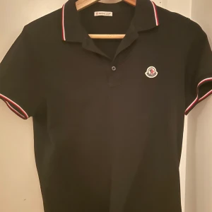 Svart pikétröja från Moncler - En klassisk piké tröja från moncler i storlek S. Tröjan är använd men i bra skick utan några defekter. Perfekt för en lite finare och stilren look. Ny pris:3500kr                            Pris kan diskuteras via snabb affär.