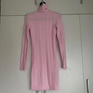 Rosa stickad klänning - Säljer en söt rosa stickad klänning med kabelstickat mönster. Klänningen har en polokrage och långa ärmar, perfekt för kyligare dagar. Den är i storlek XS och har en mysig och stilren design.säljer den pga att den var för liten men inte gick att lämna tillbaka. Aldrig använd och prislappen sitter fortfarande på. Säljer den för nästan fullpris därav