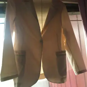 Säljer en stilren beige kavaj från Copenhagen Luxe. Kavajen har en enkel knäppning framtill och långa ärmar. Perfekt för en elegant look.
