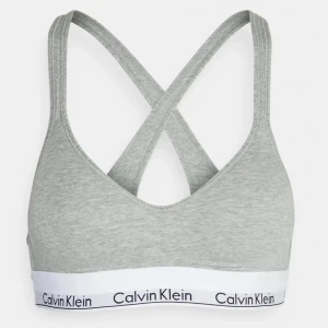 Grå sport-bh från Calvin Klein - Säljer en grå sport-bh från Calvin Klein men som även funkar som en vanlig bh, den har  korsade axelband och elastiskt band med logotyp. Perfekt för träning eller vardagsbruk. Använd en gång men tvättad efter! Köpt för 400kr säljer för 300kr❣️men kan gå ner i pris! Storlek S❣️(75B)