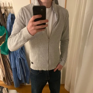 Grå hel zip - Säljer en stilren grå kofta med dragkedja från Jack&jones. Perfekt för lager-på-lager och har en bekväm passform. Den är långärmad och har ribbade muddar vid ärmslut och nederkant. Skriv om ni vill diskutera pris eller vill ha fler frågor!🙌
