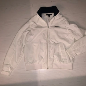 Vit vindjacka från Tommy Hilfiger - Säljer en vit vindjacka från Tommy Hilfiger med dragkedja och broderad logga på bröstet. Vid frågor eller fler bilder kontakta mig. Priset går att diskutera. 