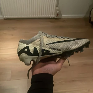Nike - Säljer ett par fotbollsskor från Adidas i beige och svart. Skorna har snörning och är designade för optimal prestanda på planen. Perfekta för fotbollsträning och matcher.