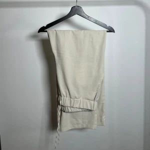 Beige byxor med snörning - Snygga beige byxor med avslappnad passform och snörning i midjan. Perfekta för en bekväm stil. Tillverkade i ett mjukt material som ger en skön känsla hela dagen.