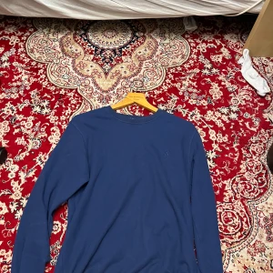 Blå långärmad tröja från Polo - Säljer en stilren blå långärmad tröja från Polo. Tröjan har en rund halsringning och är perfekt för en avslappnad stil. Passar bra till både jeans och chinos. Storlek är fel sitter som en M OBS Inte Ralph Lauren 