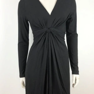 Klänning fr PEP storlek XS - Elegant svart långklänning med v-ringad hals och knutdetalj framtill. Klänningen har långa ärmar och ett stilrent fall som ger en smickrande silhuett. Perfekt för en kväll ute eller en formell tillställning. Fram n PEP. Storlek XS. Helt ny.