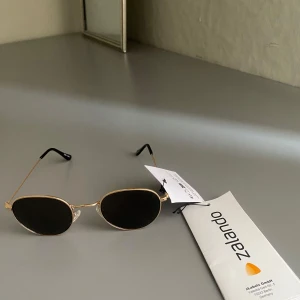 Guldiga solglasögon från Zalando - Snygga och stilrena solglasögon med guldfärgad metallram och mörka linser. Perfekta för en solig dag och ger en klassisk look. Passar till alla outfits och är ett måste i sommar! 😎