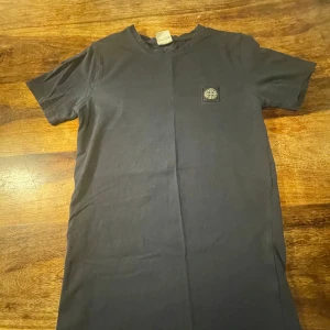 Mörkblå t-shirt från Stone Island - Säljer en stilren mörkblå t-shirt från Stone Island i mycket bra skick. Den har en klassisk passform med korta ärmar och en liten logga på bröstet. Perfekt för både vardag och fest! 🖤