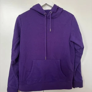 Lila hoodie - Säljer en snygg lila hoodie i bra skick. Den har en klassisk design med känguruficka och justerbar huva med snören.