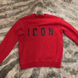 Röd sweatshirt från DSQUARED2 ICON - Säljer en snygg röd sweatshirt från DSQUARED2 med texten 'ICON' i svart på framsidan. Tröjan är använd ett par gånger men är i mycket bra skick. Nypris är på cirka 3000 kronor!