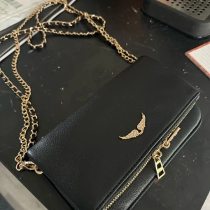  Zadig & Voltaire väska - Snygg svart axelväska med guldfärgade kedjedetaljer. Dustbag med följer. Pris kan diskuteras. Använd 1 gånger inga defekter.