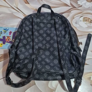 Svart ryggsäck från Guess - Snygg svart ryggsäck från Guess med ett stilrent mönster och dragkedja. Perfekt för vardagsbruk eller en dag på stan. Ryggsäcken har justerbara remmar och flera fack för enkel organisering. Den är i mycket bra skick och redo för nya äventyr!