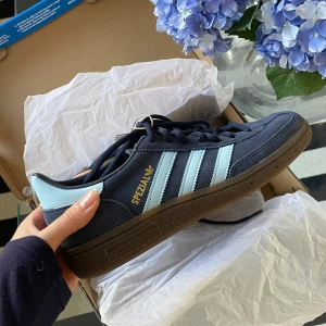 Adidas Handball Spezial - Säljer ett par helt nya Adidas Handball Spezial i mörkblått med ljusblå ränder. kommer i originalkartong + lappar kvar. Säljes då jag redan har ett par av dessa och då jag fått dessa.