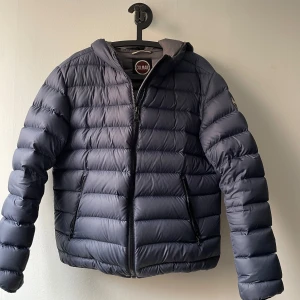 Mörkblå pufferjacka från Colmar - Säljer en snygg mörkblå pufferjacka från Colmar i storlek 52. Jackan är i bra skick, men finns en defekt på ena ärmen som dock inte syns speciellt mycket. Det är också lite slitet på märket så därav de billiga priset. Köpte jackan för ca 6000kr men kvittot finns tyvärr inte kvar. Skriv gärna om det finns några funderingar!