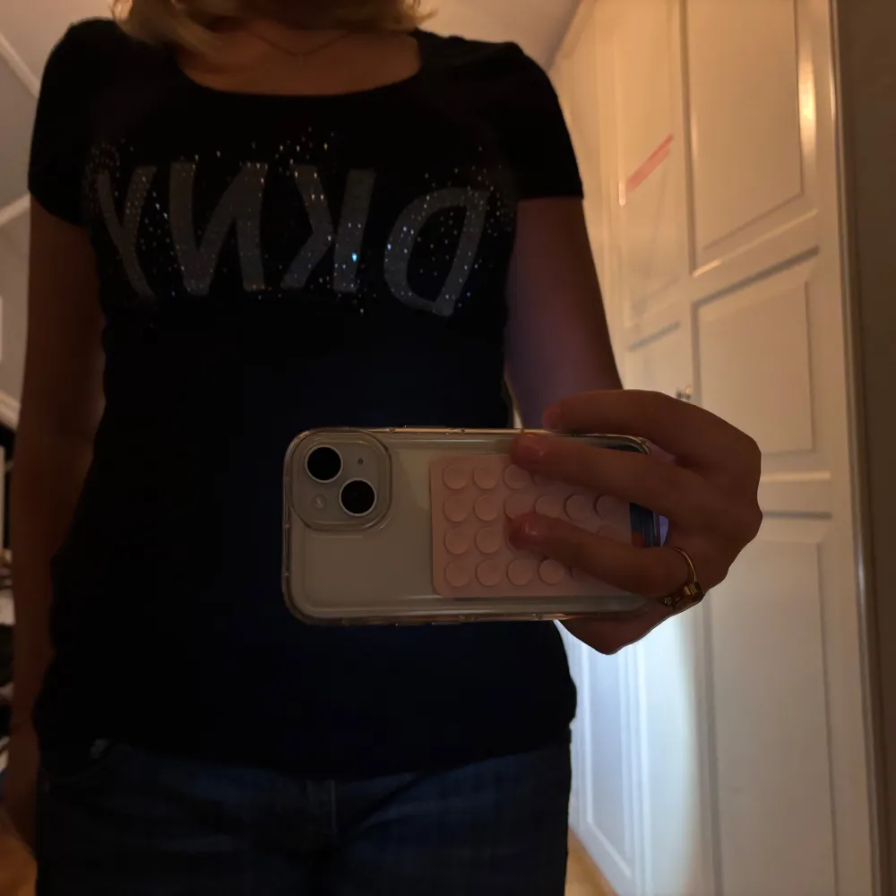 Snygg svart t-shirt från DKNY med glittrande logga framtill. Perfekt för en casual look eller att klä upp med accessoarer. T-shirten har en normal passform och korta ärmar. Ett måste i garderoben för alla som älskar stil och komfort!. T-shirts.